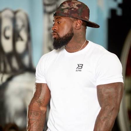 Mike Rashid wearing a white Alpha shirt and a camouflage cap in the gym