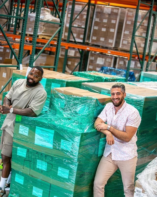 Mike Rashid and a colleague beside wrapped pallets of Ambrosia boxes in a warehouse