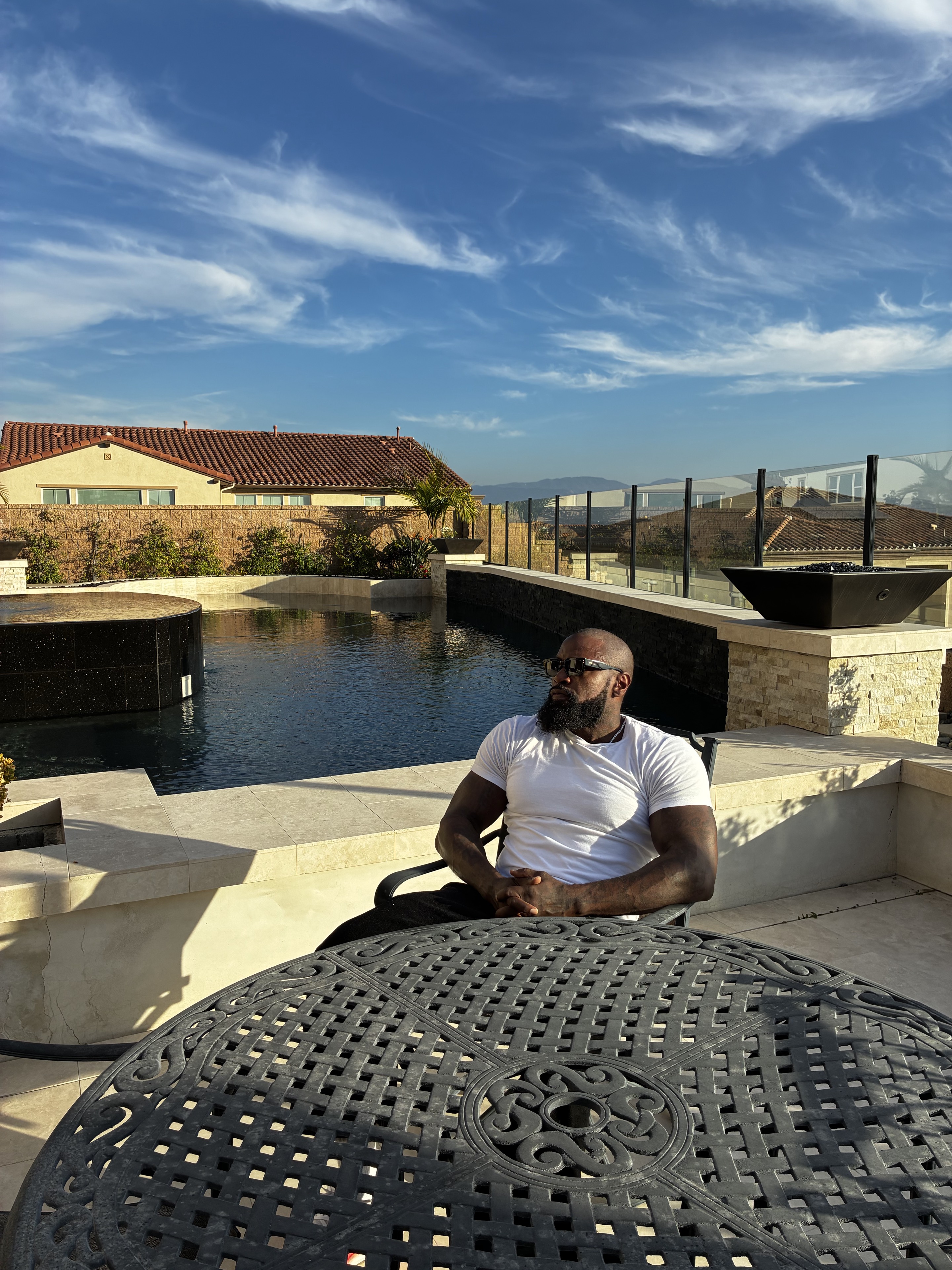 Mike Rashid seated beside a pool beneath an open blue sky